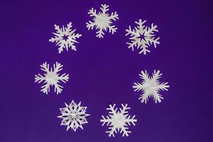 vitt pappers snöflingor olika former och storlekar på violett bakgrund. toppvy. foto