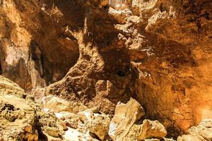 granitkalksten i grottan, men solljuset lyser starkt och visar de konkava kurvorna och formerna hos de naturligt vackra stenarna av stalagmiter och stalaktiter. foto
