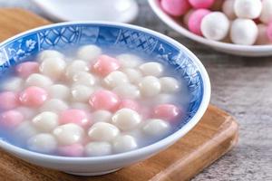 närbild av röd och vit tangyuan i blå skål på trä bakgrund för vintersolståndet. foto