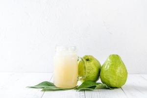 utsökt guava frukt med färsk juice på vit träbord bakgrund. foto