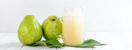 utsökt guava frukt med färsk juice på vit träbord bakgrund. foto