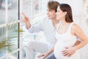 le gravid kvinna tittar på fönstret med sin man foto