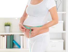 gravid kvinna mäter magen foto