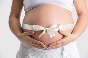 närbild skott gravid mage lindad med satin dekorativ ribbo foto