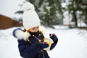 ett barn på vintern på en snöig gata under ett snöfall i en glödande krans med stjärnor. förberedelse för julhelgen, nyår. festlig stämning, förväntan på ett mirakel foto