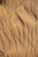textur av sand i öknen närbild bakgrund. en dyn med ett mönster av sandvågor foto