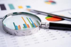 förstoringsglas på diagram diagrampapper. finansiell utveckling, bankkonto, statistik, investeringsanalys, forskningsdataekonomi, börshandel, affärskontorsföretagskoncept. foto