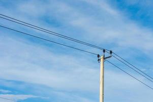elektrisk stolpe med ledningar mot blå himmel foto