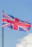 Förenade kungarikets nationella flagga vajar över den blå himlen foto