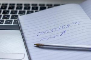 inflation skrev ord på en handbok med anteckningsbok, penna och anteckningsbok foto