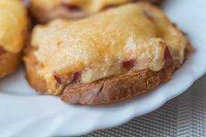 närbild av bakade varma smörgåsar med ost och korv på vit platta foto