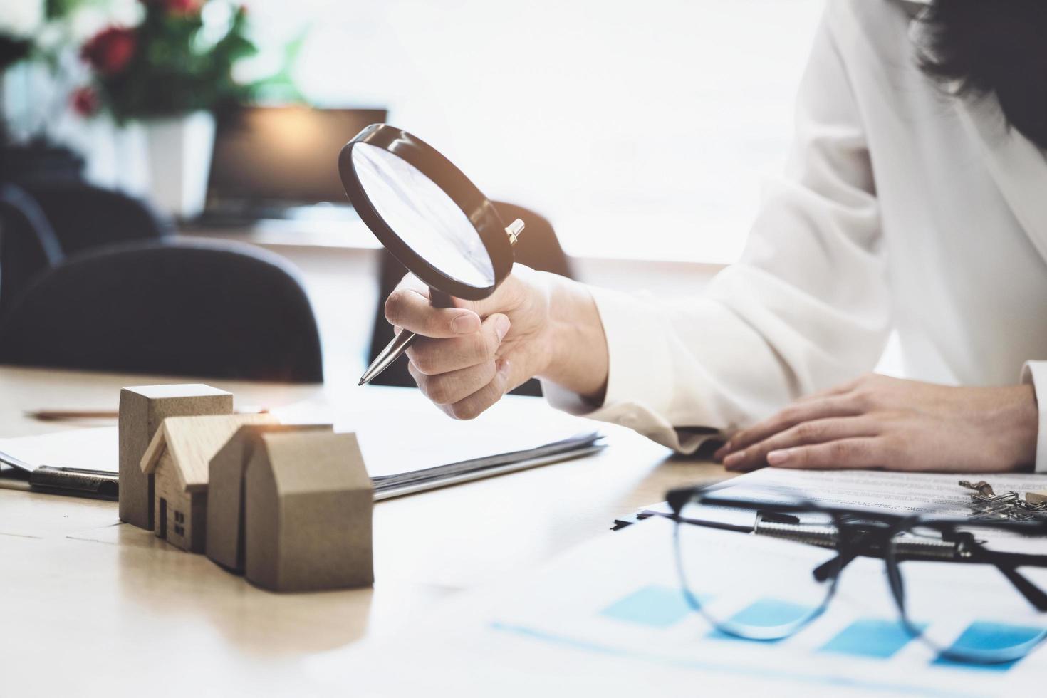 inspecteur-concept, een klant houdt een vergrootglas vast om naar elk huismodel te kijken om de prijs van een woningkrediet voor elk model te controleren. foto