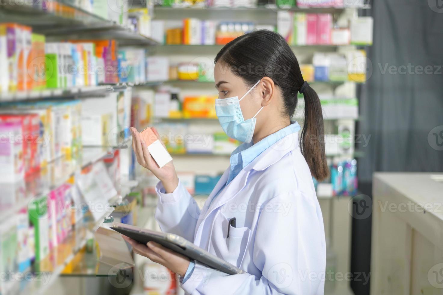 portret van vrouwelijke apotheker die gezichtsmasker draagt in een moderne apotheekdrogisterij. foto