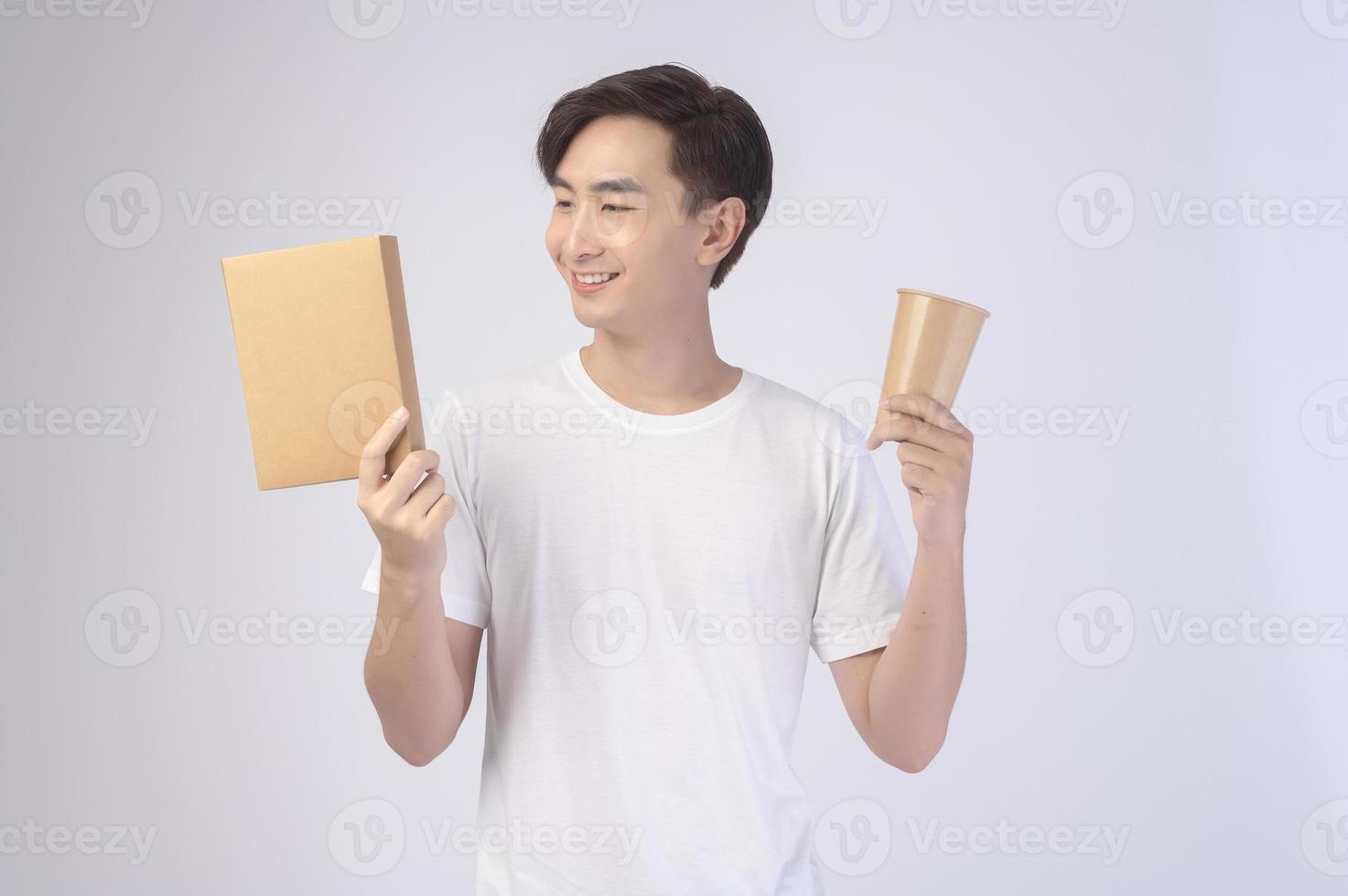 jonge aziatische man met een papieren beker en een papieren doos op een witte achtergrond, bewaar het concept van de aarde foto