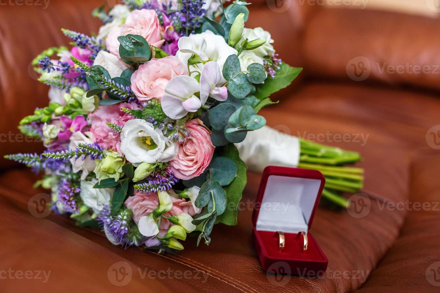 helder bruidsboeket van zomerse witroze rozen en orchidee met violette wilde bloemen met trouwringen foto