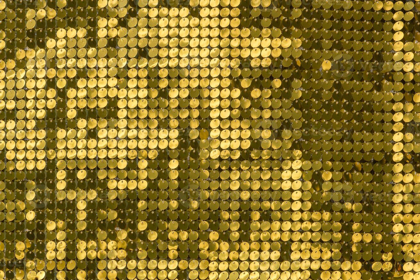 rijen knipperende goudgele koperen metalen platen zwaaien in de wind en schijnen in de zon en creëren een uniek bewegingspatroon. ronde reflecterende deeltjes textuur glitter onder golven van wind. lovertjes glitter foto