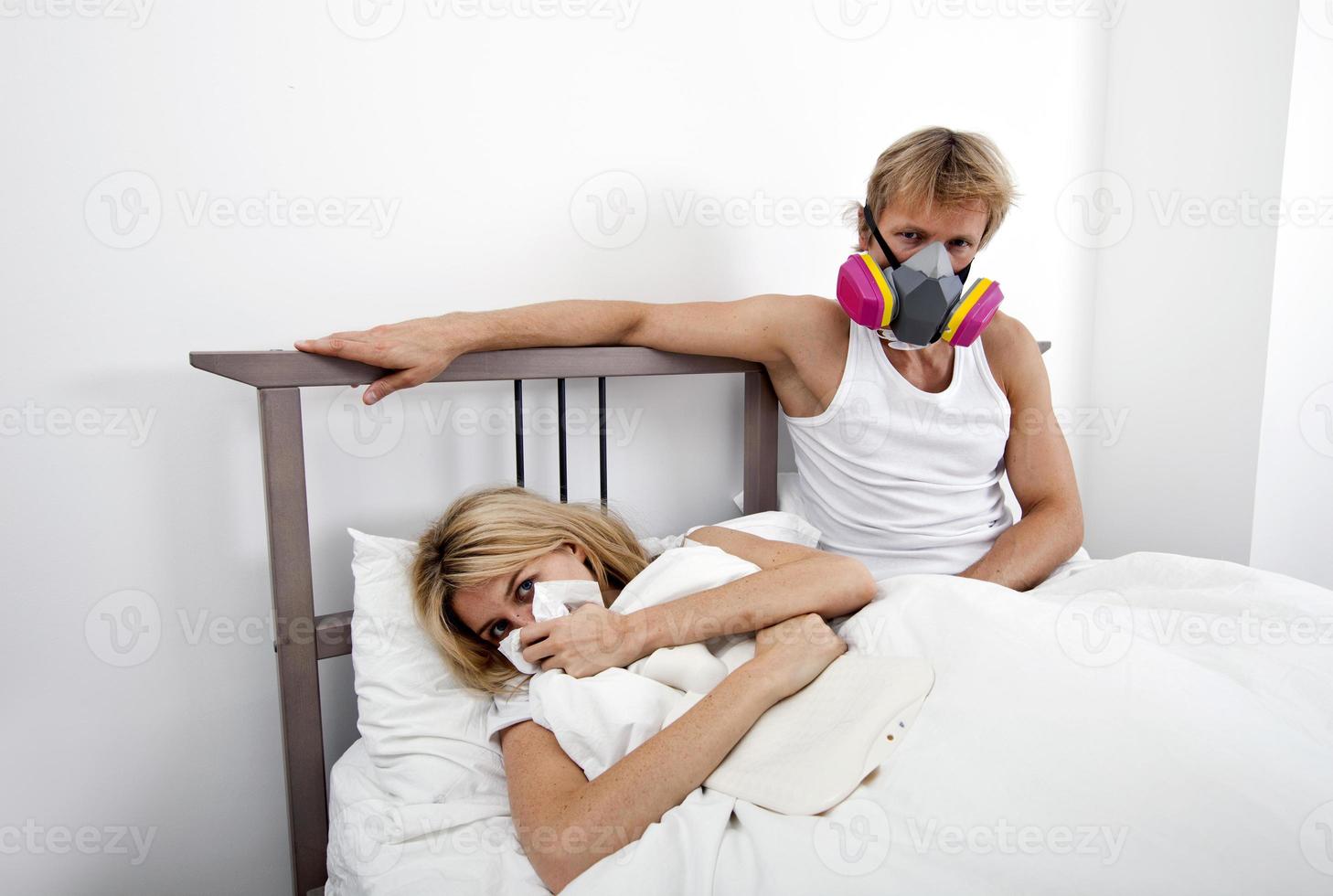 man met gasmasker terwijl vrouw die lijdt aan kou foto