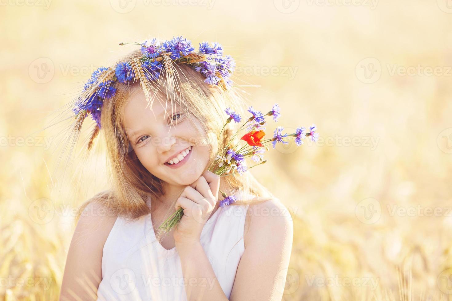gelukkig meisje met bloemen kroon op zomer tarweveld foto