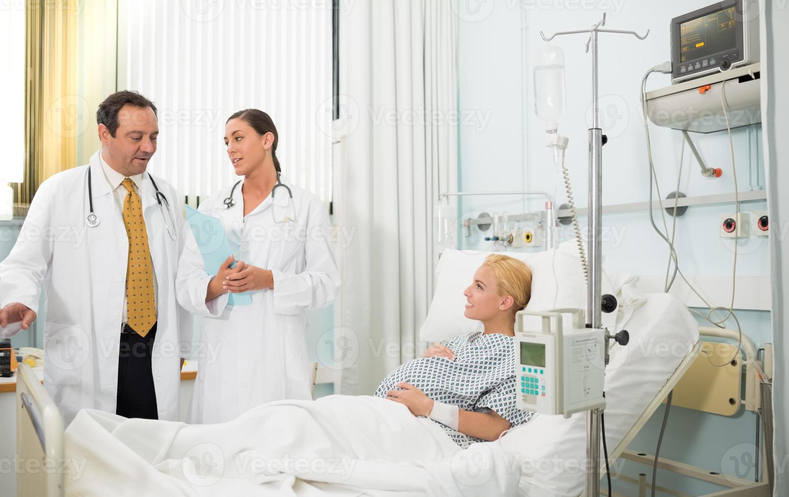 zwangere patiënt in haar bed te praten met artsen foto