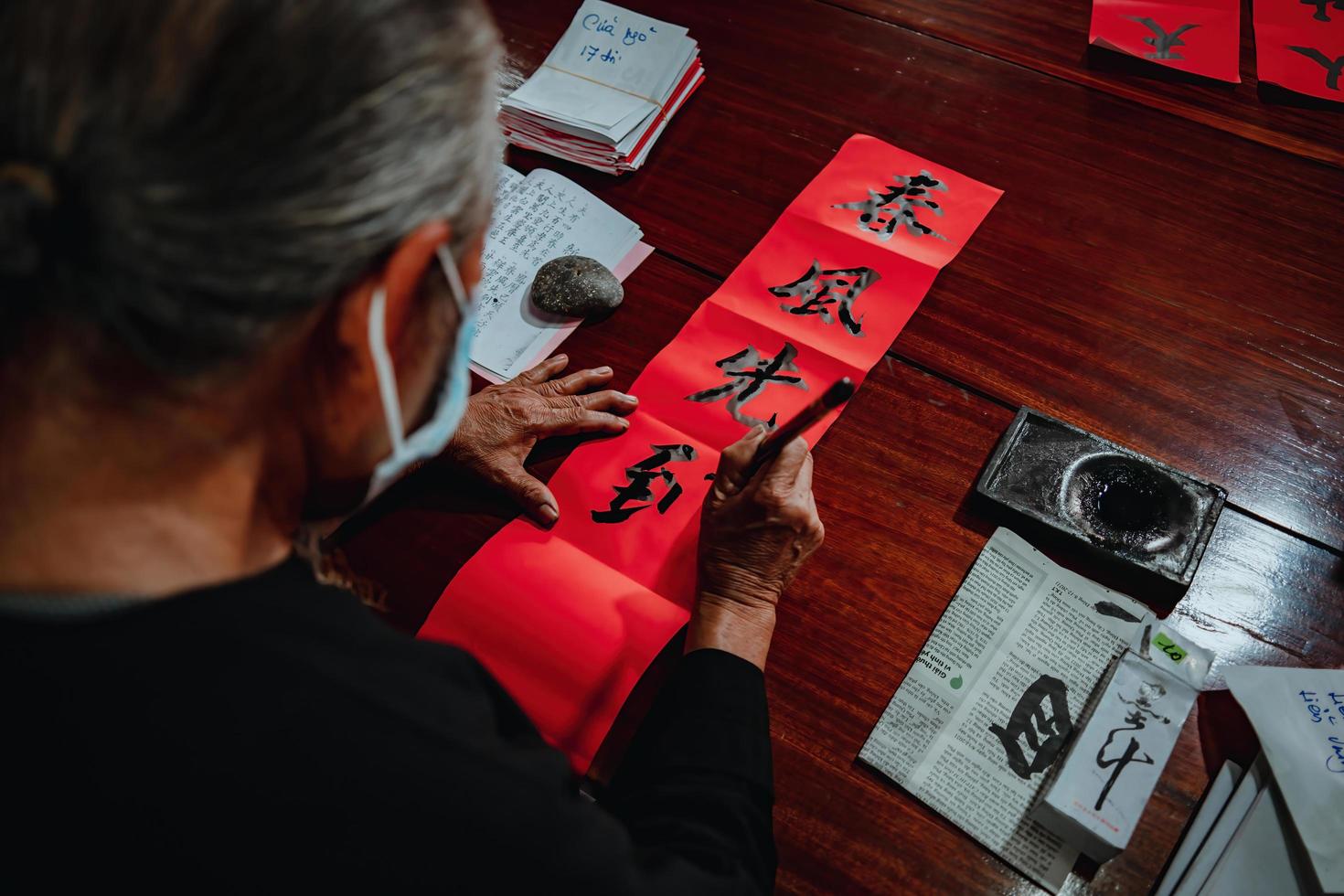 Vietnamese geleerde schrijft kalligrafie bij lange zoon. kalligrafiefestival is een populaire traditie tijdens tet-vakantie. schrijven van coupletten voor lentefestival, nieuwjaar. foto
