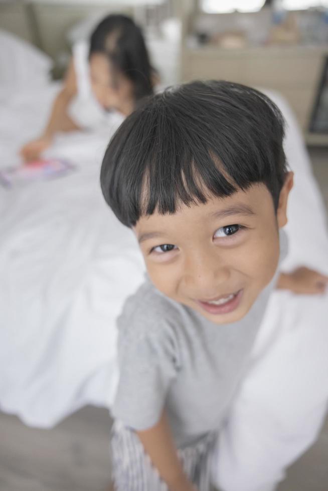 close-up van lachende kleine Aziatische jongen kijken in de camera grijze kleding dragen. portret van gelukkige schattige jongen foto