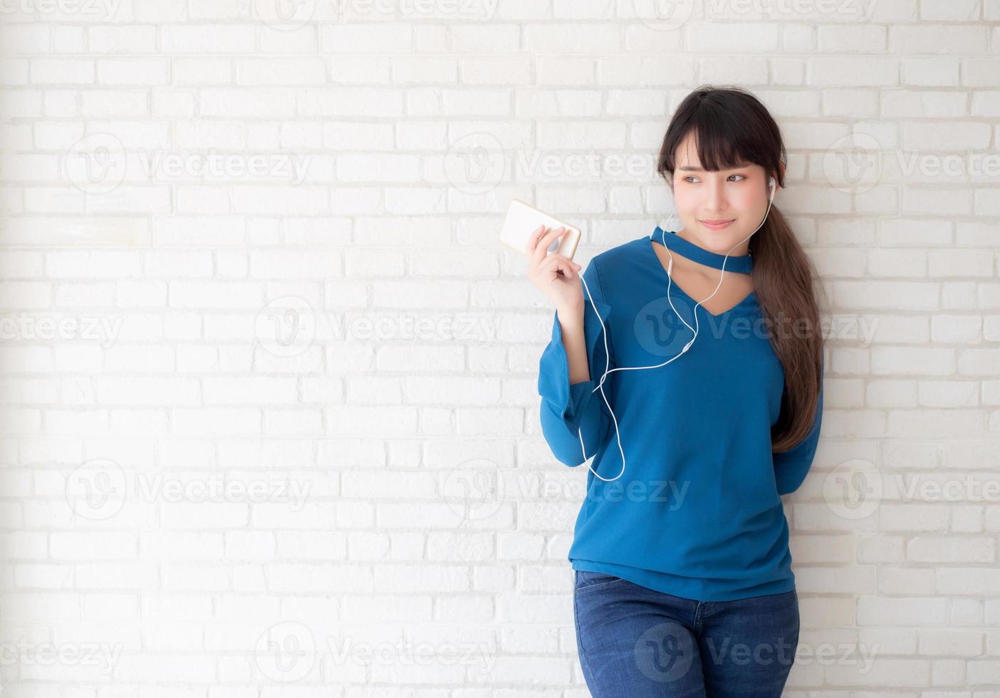 mooi portret aziatische jonge vrouw staande gelukkig genieten en plezier luisteren muziek met koptelefoon op cement betonnen achtergrond, levensstijl van meisje ontspannen geluid radio met oortelefoon, technologie concept. foto