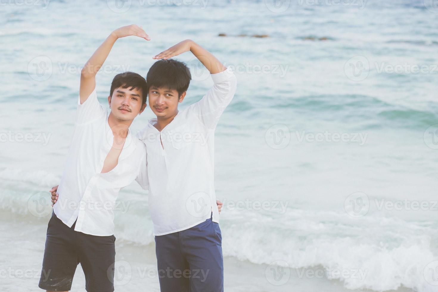 homoseksueel portret jong aziatisch koppel staan gebaar hartvorm samen op het strand in de zomer, azië gay knuffel en gaan op zee voor vrije tijd met romantisch en gelukkig in vakantie, lgbt met juridisch concept. foto
