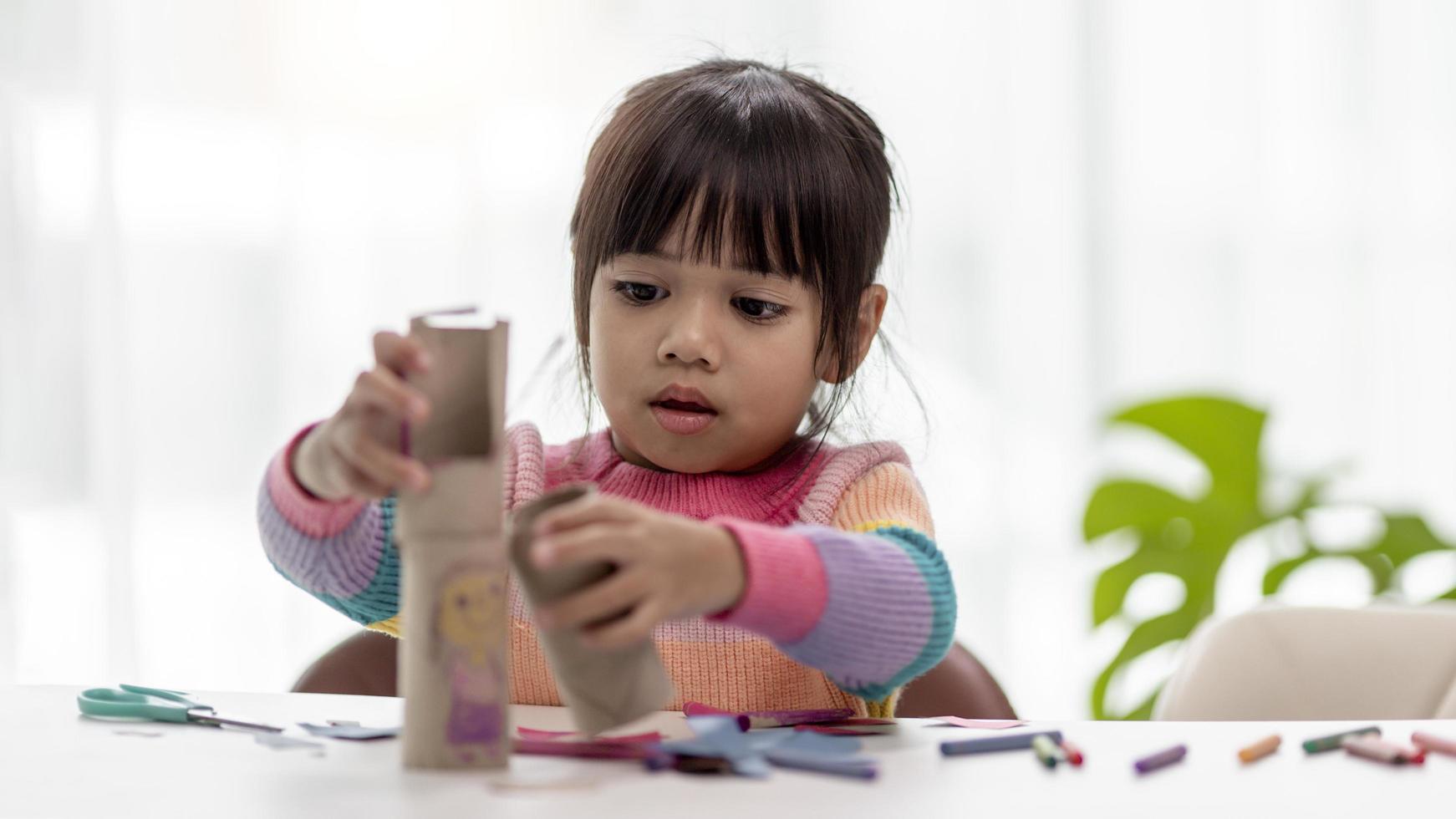 kleine aziatische meisjes maken verrekijkers van papieren zakdoekjes. afvalproducten hergebruiken. idee op maat gemaakt speelgoed. zachte focus. foto