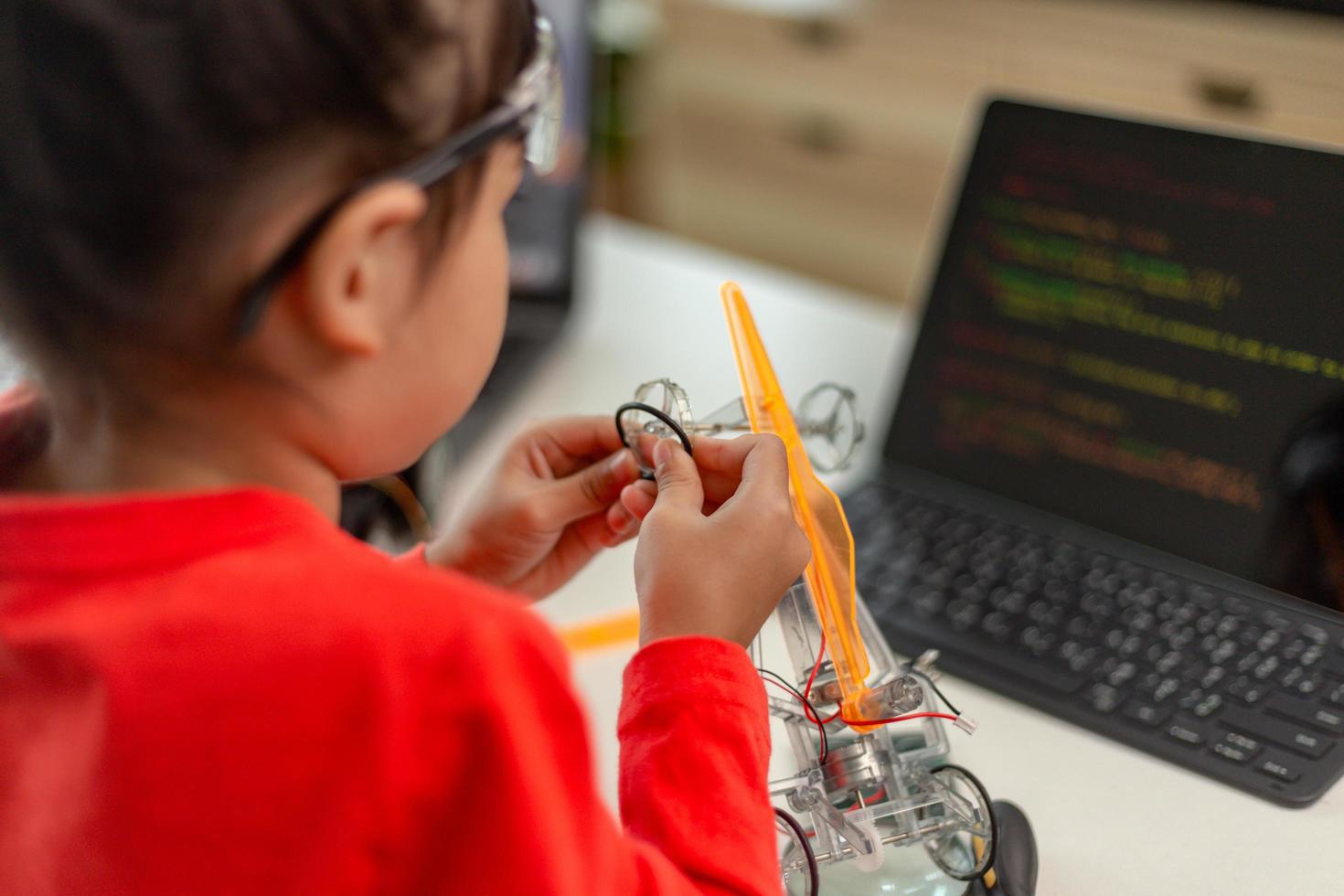 azië studenten leren thuis in het coderen van robotauto's en elektronische bordkabels in stam, stoom, wiskunde engineering wetenschap technologie computercode in robotica voor kinderen concept. foto