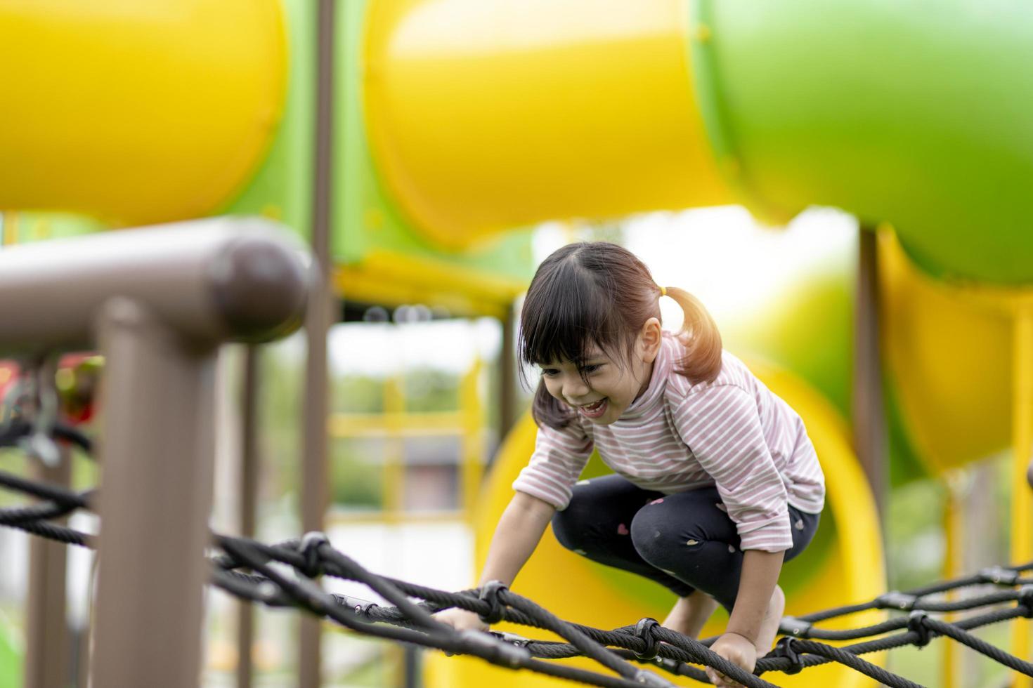 kind spelen op buitenspeeltuin. kinderen spelen op school of kleuterschool. actieve jongen op kleurrijke glijbaan en schommel. gezonde zomeractiviteit voor kinderen. kleine jongen buiten klimmen. foto