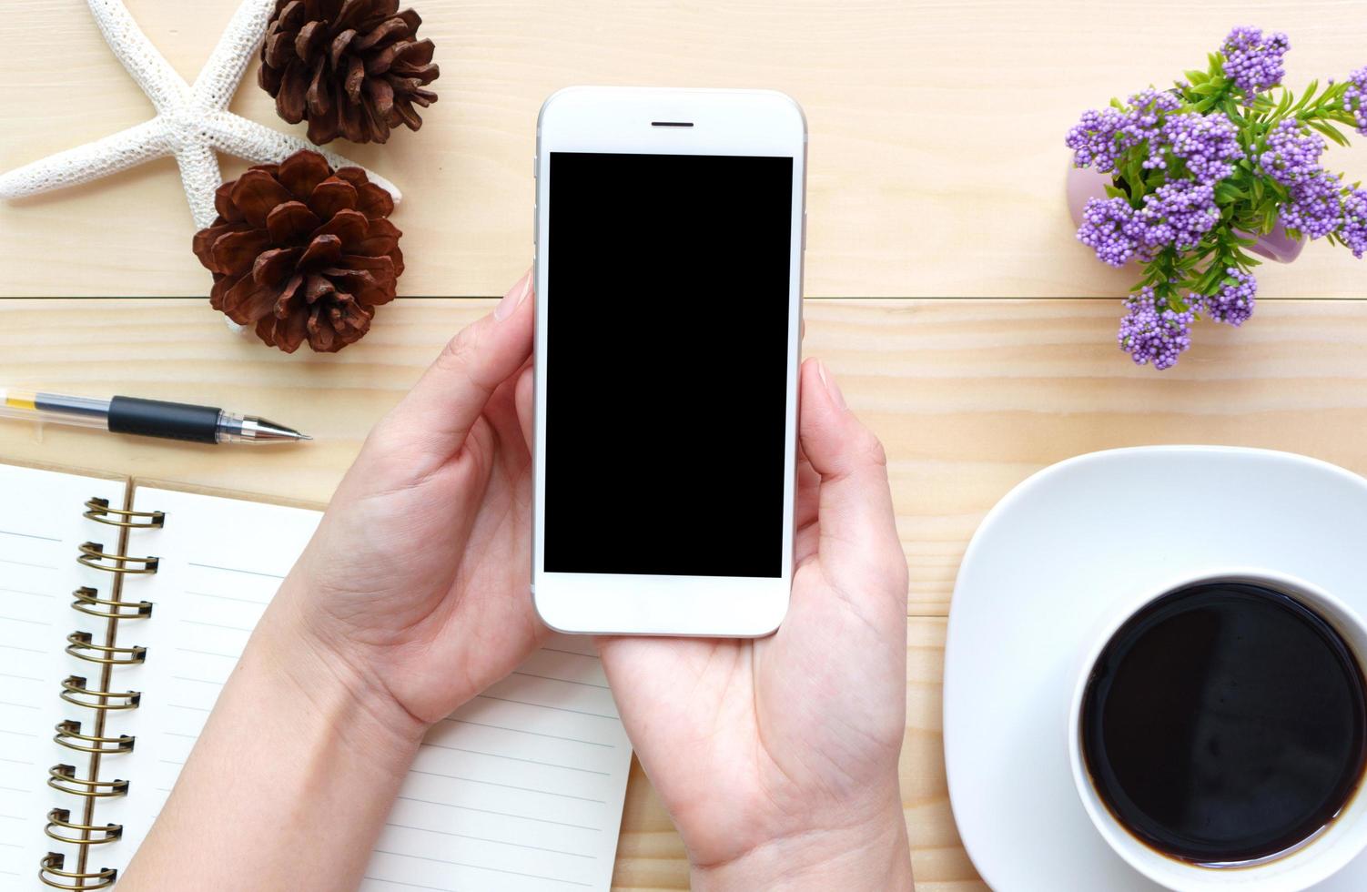 vrouw handen met leeg scherm van smartphone op houten bureau werk. foto