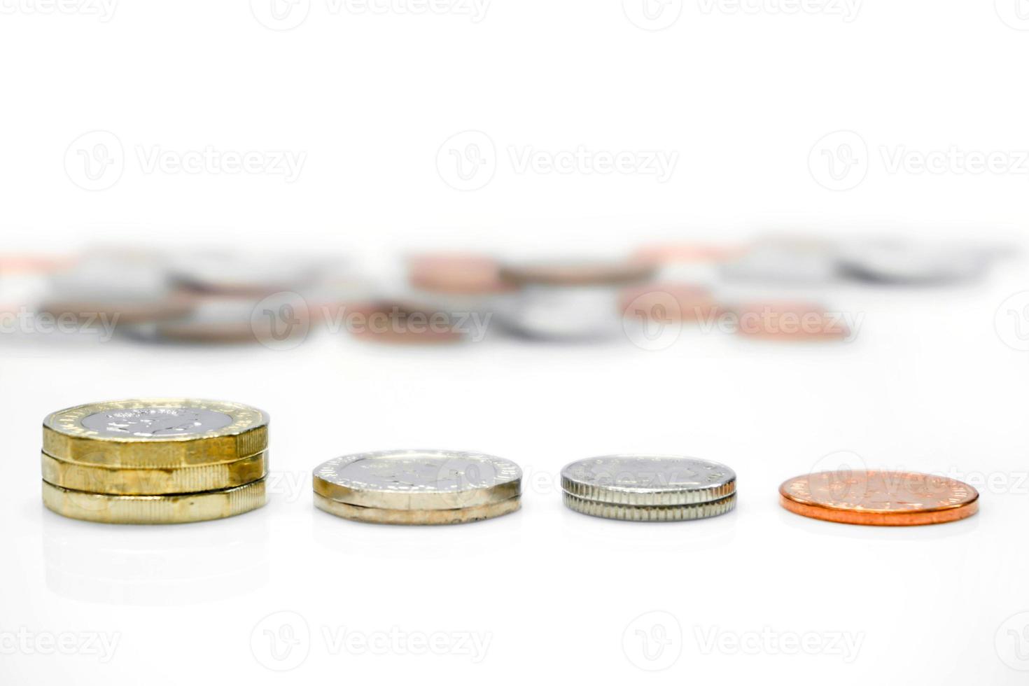 zijaanzicht en line-up van Britse valuta munten met wazige munt achter en isoleren op een witte achtergrond. muntopstelling is als de economie van het land. foto