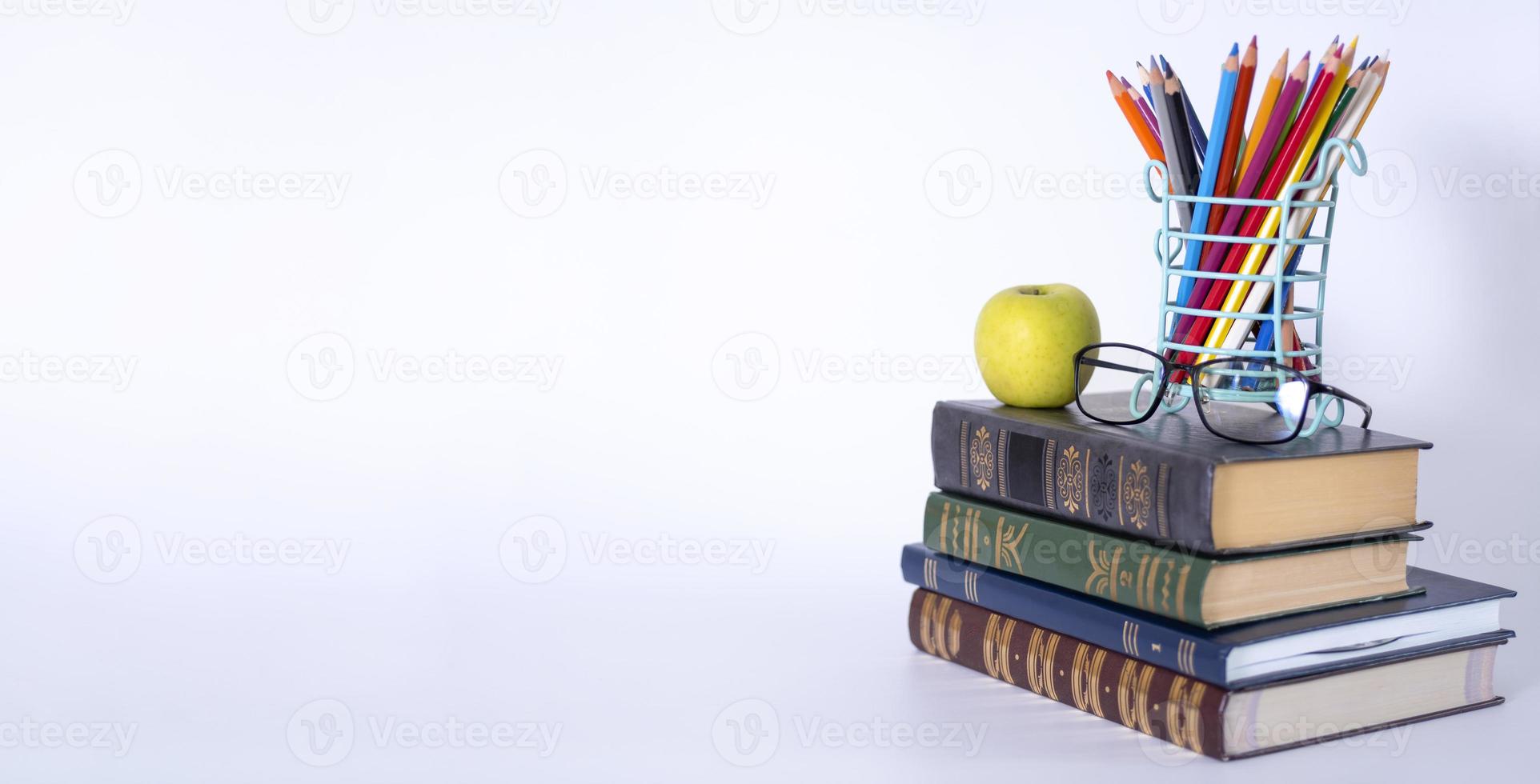 een stapel boeken, studiegidsen, studieboeken, brillen en potloden in een houder voor tekstkopieën. foto