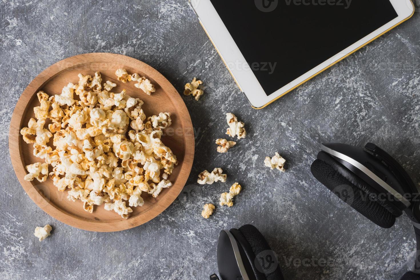 popcorn met witte tablet en koptelefoon op grunge achtergrond. foto