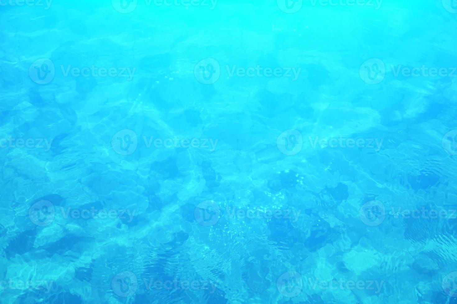 defocus wazig blauw water schijnt in de zee. golfde water detail achtergrond. het wateroppervlak in de zee, oceaan achtergrond. watergolf onder de achtergrond van de overzeese textuur. foto