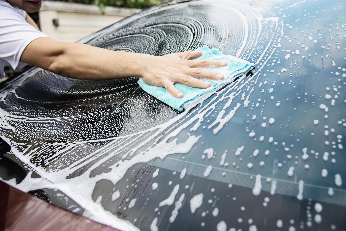 man wast auto met shampoo - autoverzorgingsconcept voor het dagelijks leven foto