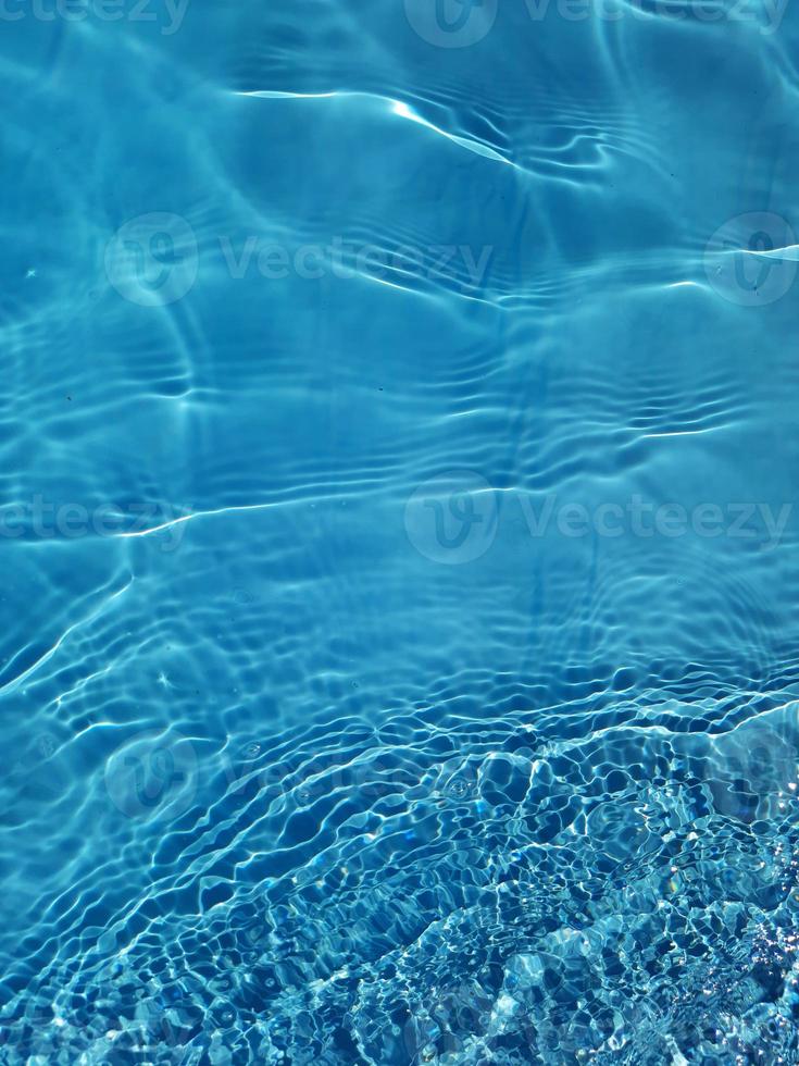 defocus wazig blauw water schijnt in de zee. golfde water detail achtergrond. het wateroppervlak in de zee, oceaan achtergrond. watergolf onder de achtergrond van de overzeese textuur. foto