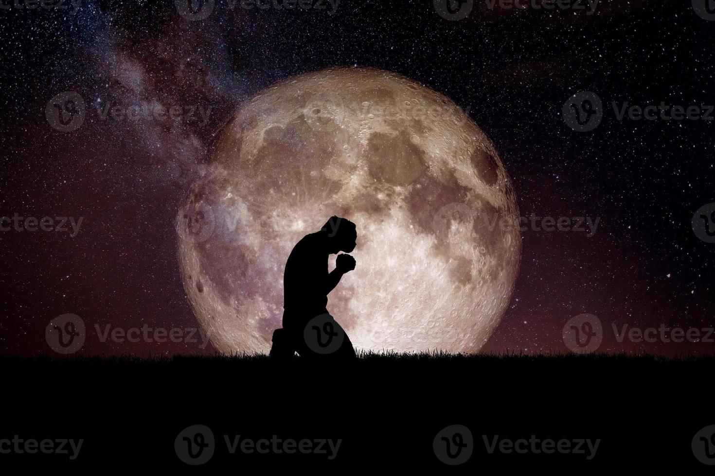 een wanhopige en eenzame man knielde neer en bad tot god. er is 's nachts een maan op de achtergrond. wanhopige, hartverscheurende en eenzame concepten foto