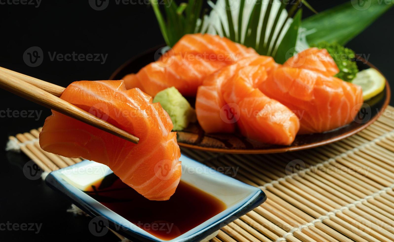 sashimi, zalm, japanse eetstokjes en wasabi op de houten tafel foto