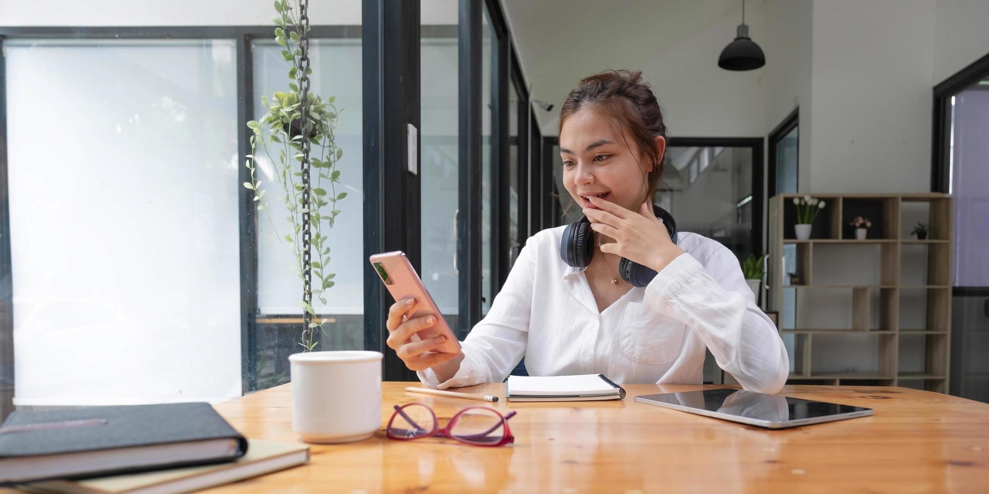 gelukkig jong aziatisch tienermeisje zit thuis op de bank met telefoon en kijkt naar het scherm zwaaiende hand videobellen afstand vriend online in mobiele chat-app met behulp van smartphone videochat-applicatie. foto