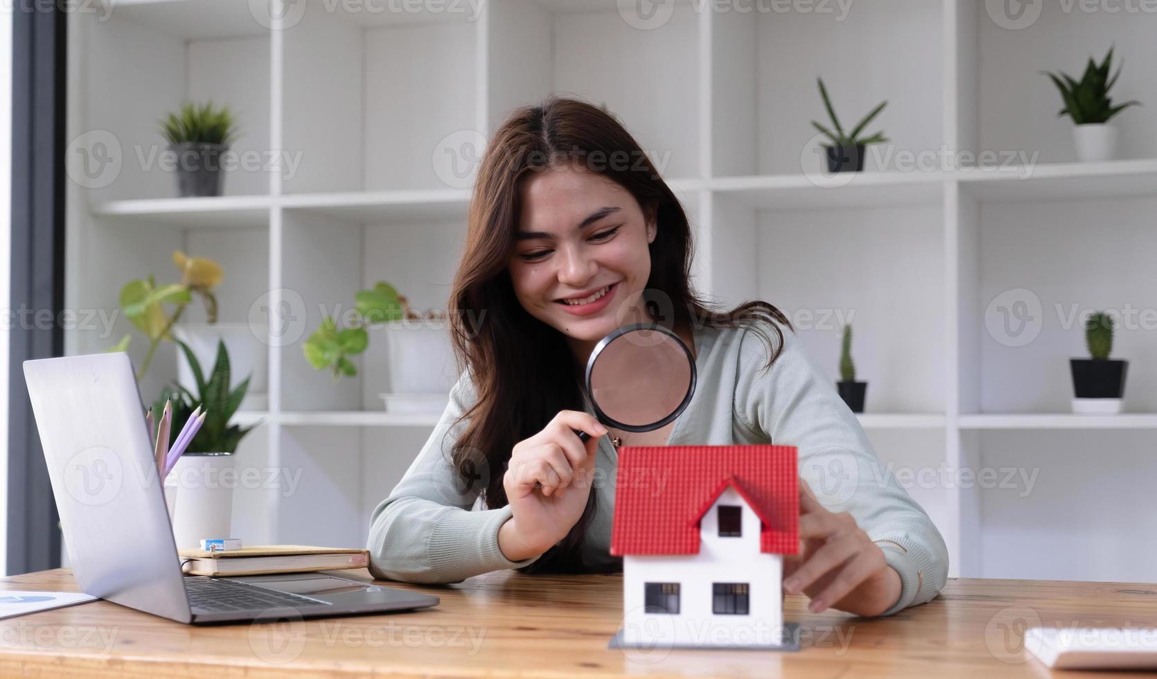 gelukkige vrouw hand met vergrootglas en kijken naar huis model, huis selectie, onroerend goed concept. foto