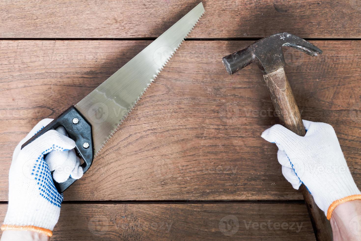 handen met hamer en zaag op houten tafel achtergrond. foto