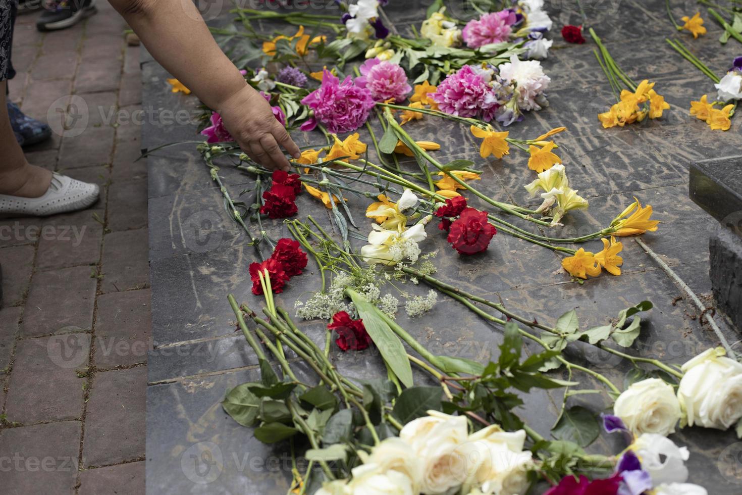 bloemen op grafsteen leggen. bloemen tijdens de ceremonie. graf van onuitputtelijke soldaat in rusland. foto