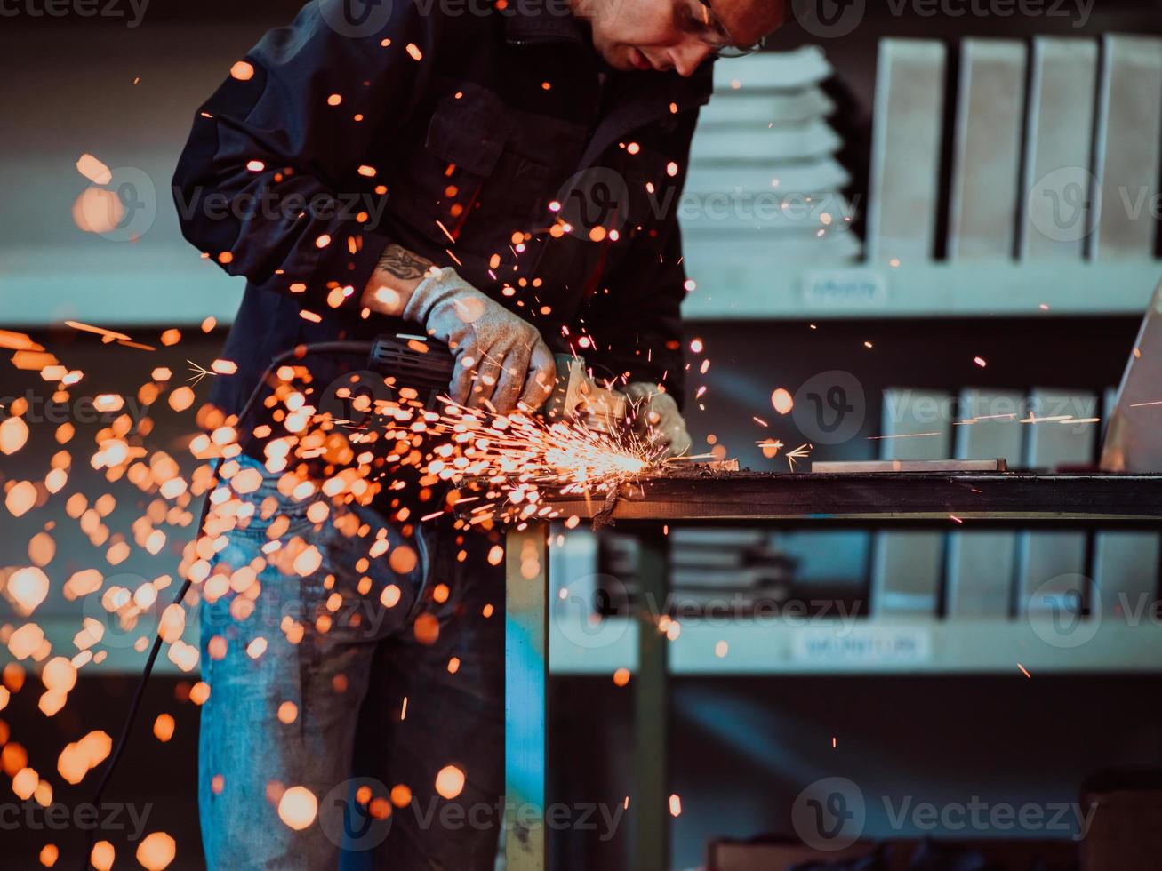 zware industrie engineering fabrieksinterieur met industriële werknemer die haakse slijper gebruikt en een metalen buis snijdt. aannemer in veiligheidsuniform en bouwhelm voor het vervaardigen van metalen constructies. foto