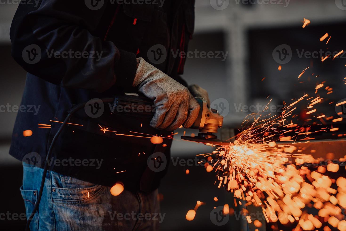 zware industrie engineering fabrieksinterieur met industriële werknemer die haakse slijper gebruikt en een metalen buis snijdt. aannemer in veiligheidsuniform en bouwhelm voor het vervaardigen van metalen constructies. foto