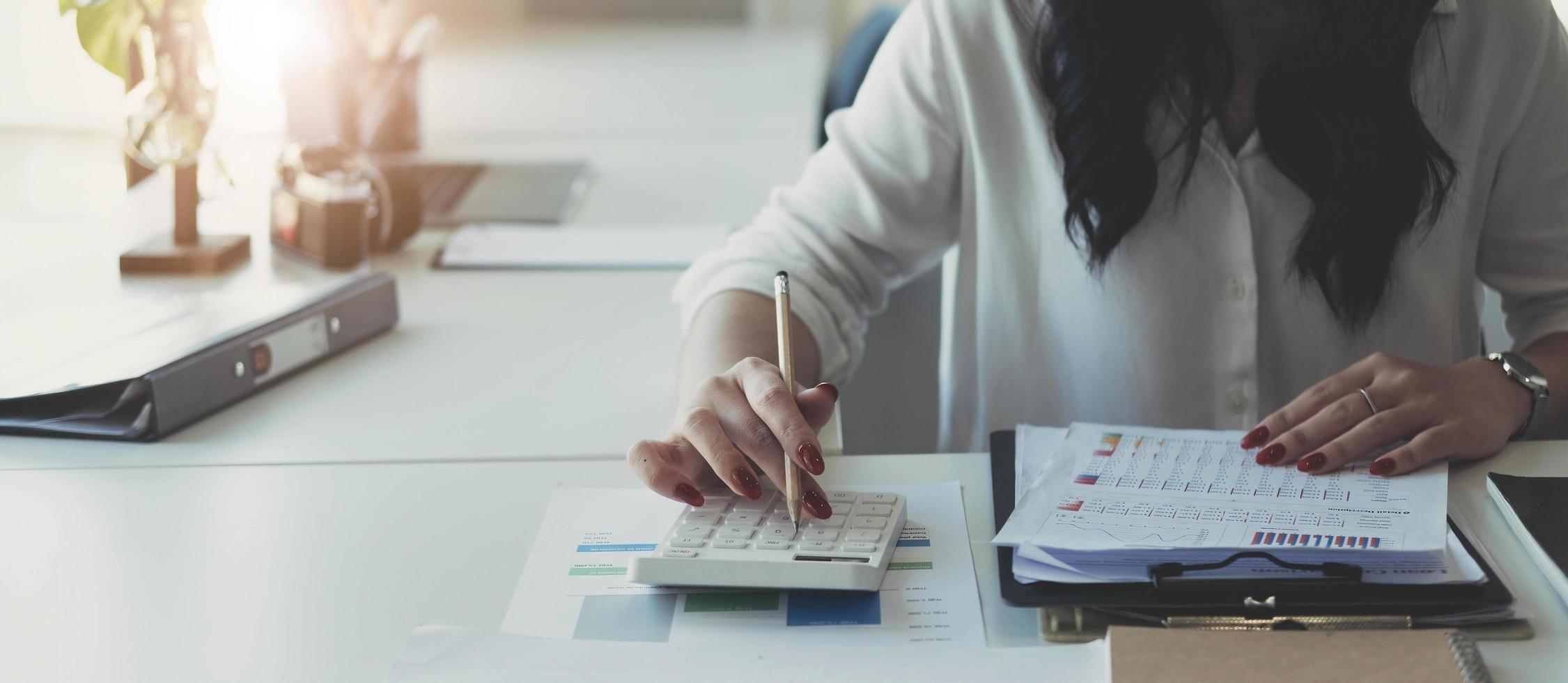 close-up van zakenvrouwhanden die een rekenmachine gebruiken om de bedrijfsfinanciën en -inkomsten en -budget te controleren. zakenvrouw die maandelijkse uitgaven berekent, budget, papieren, leningdocumenten, facturen beheert. foto