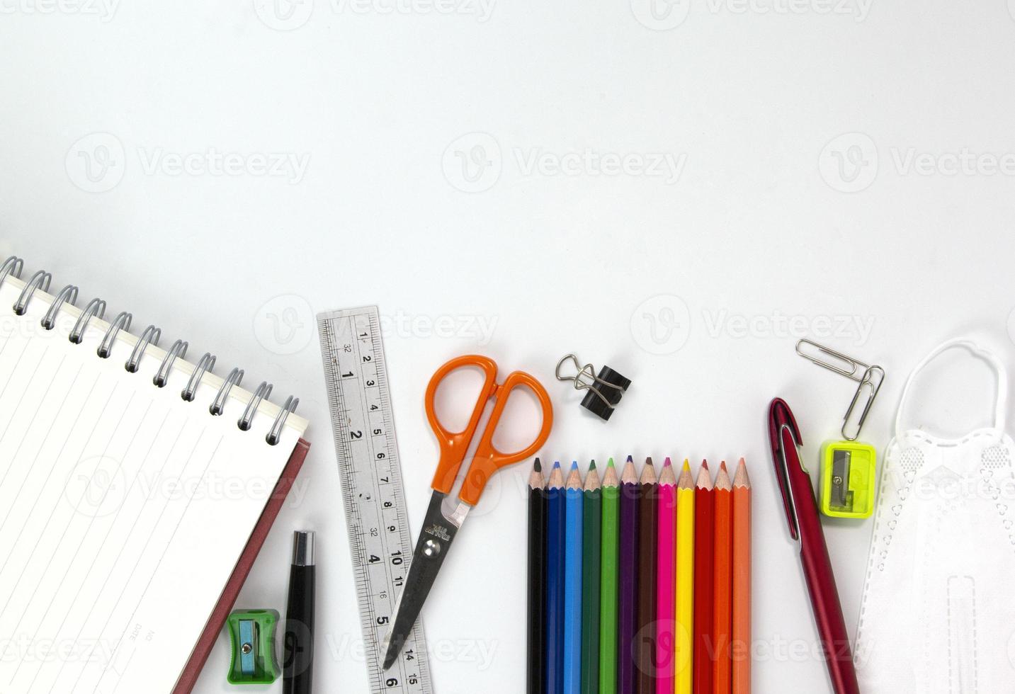 set onderwijselementen, kleurrijke potloden, gezichtsmasker, paperclips, schaar, liniaal geïsoleerd op een witte achtergrond. terug naar schoolconcept foto
