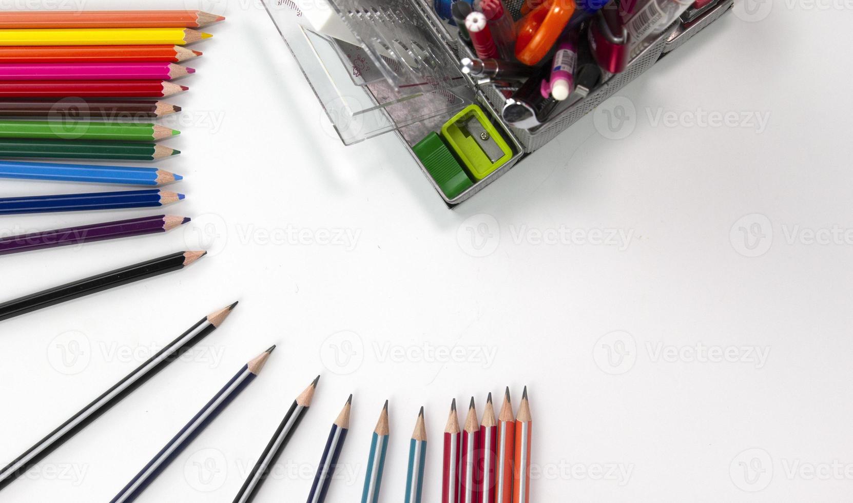 creatieve kleurpotlodenpositie met onderwijselementen op witte backgroup. gebruikt in terug naar school concept. bovenaanzicht van veelkleurige potloden geïsoleerd op een witte achtergrond foto