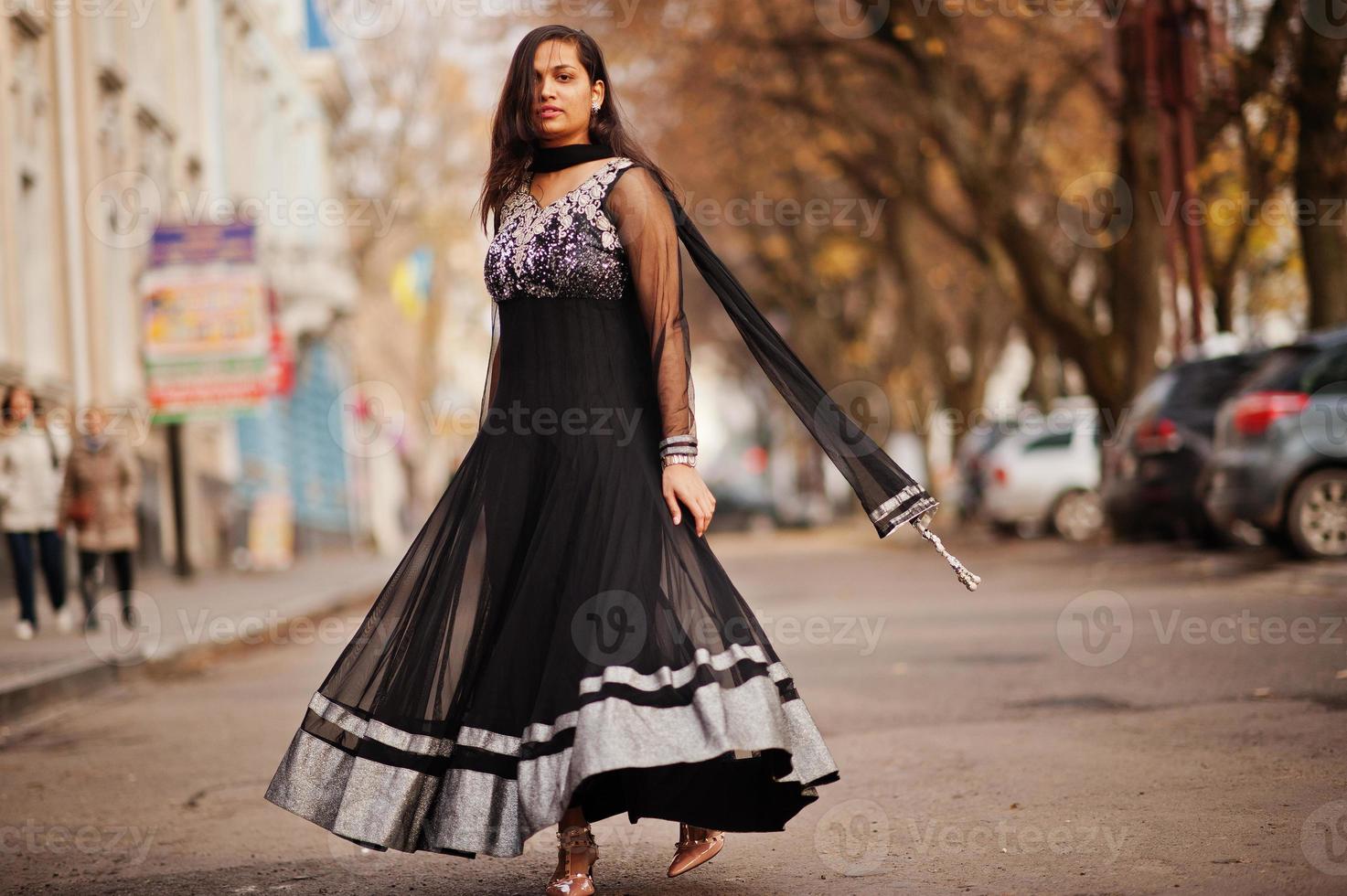 vrij indisch meisje in zwarte saree-jurk poseerde buiten in de herfststraat. foto