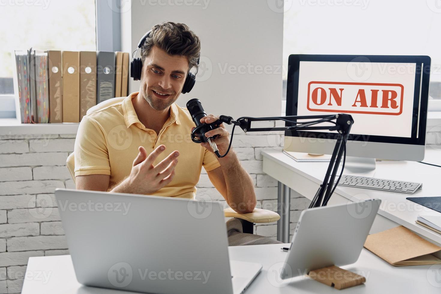 knappe jonge man met microfoon en gebaren tijdens het opnemen van podcast in studio foto